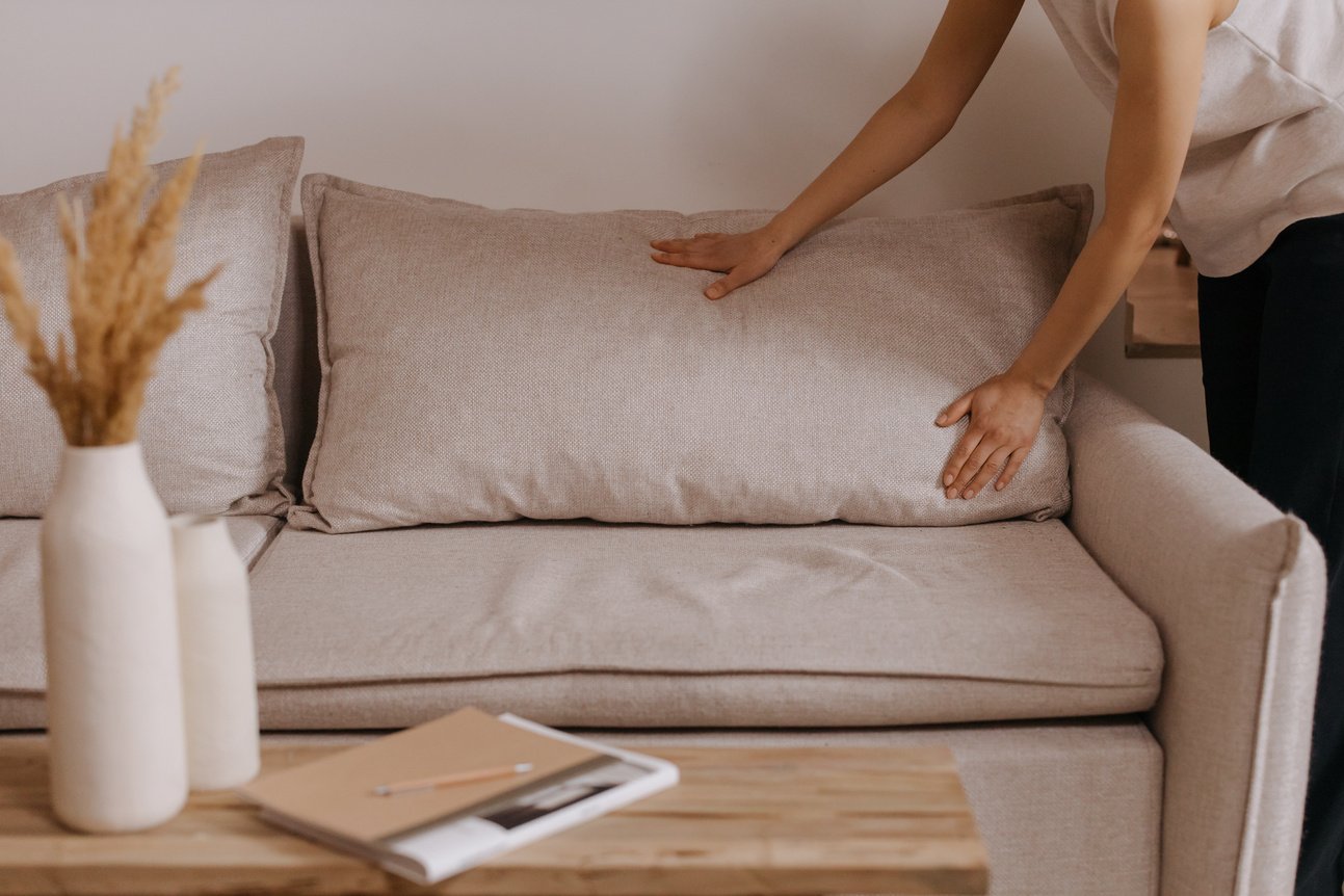 A Person Arranging the Pillow of a Sofa